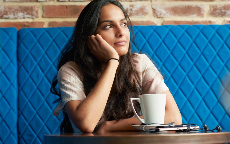Woman sitting in booth with hand on cheek