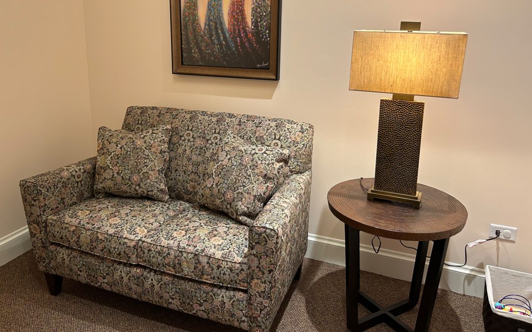 seating area with a small patterned couch and lamp