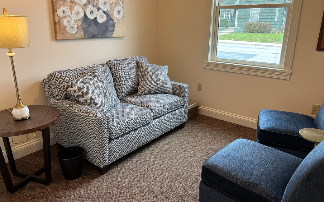 counseling room with small patterned couch and navy chairs