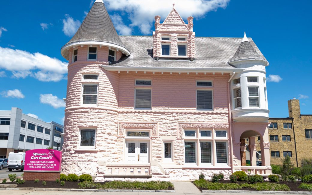 historical downtown building painted pink with Women's Care Center sign in front