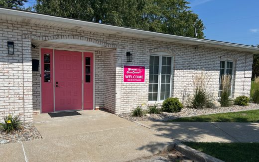 exterior of white brick building with pink door